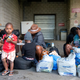 A group of Haitian asylum seekers sit with shopping bags outside the Olympic Stadium, which is being used for temporary housing for asylum seekers, in Montreal